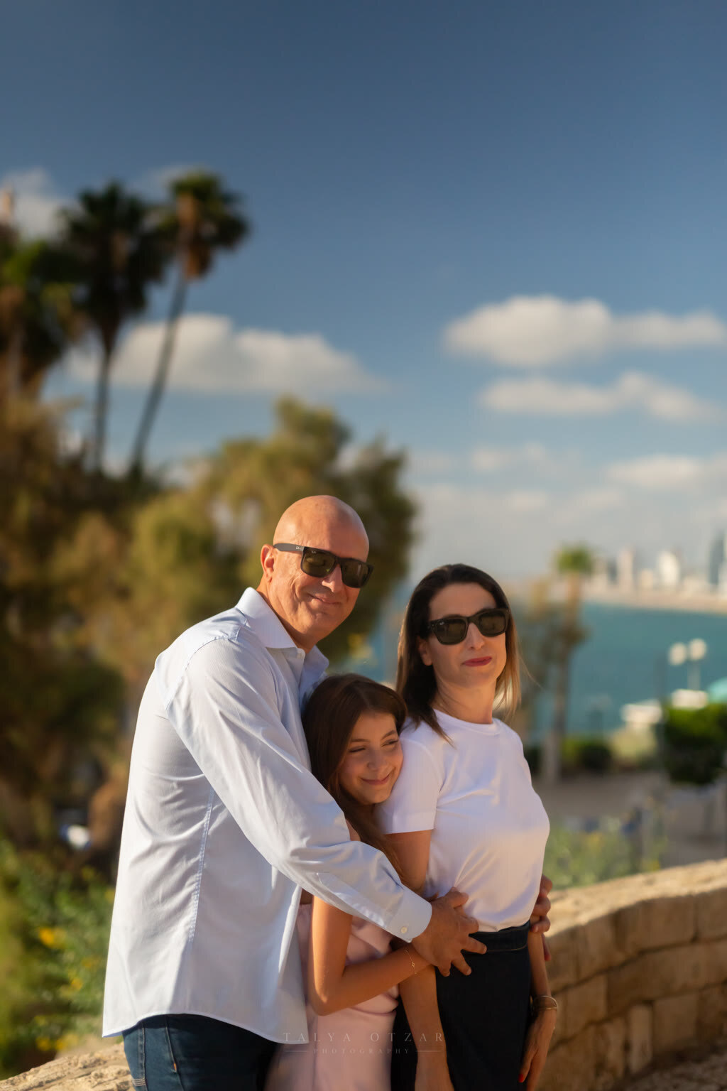 Mother, father and daughter together on the Jaffa promenade, the Tel Aviv coastline behind them