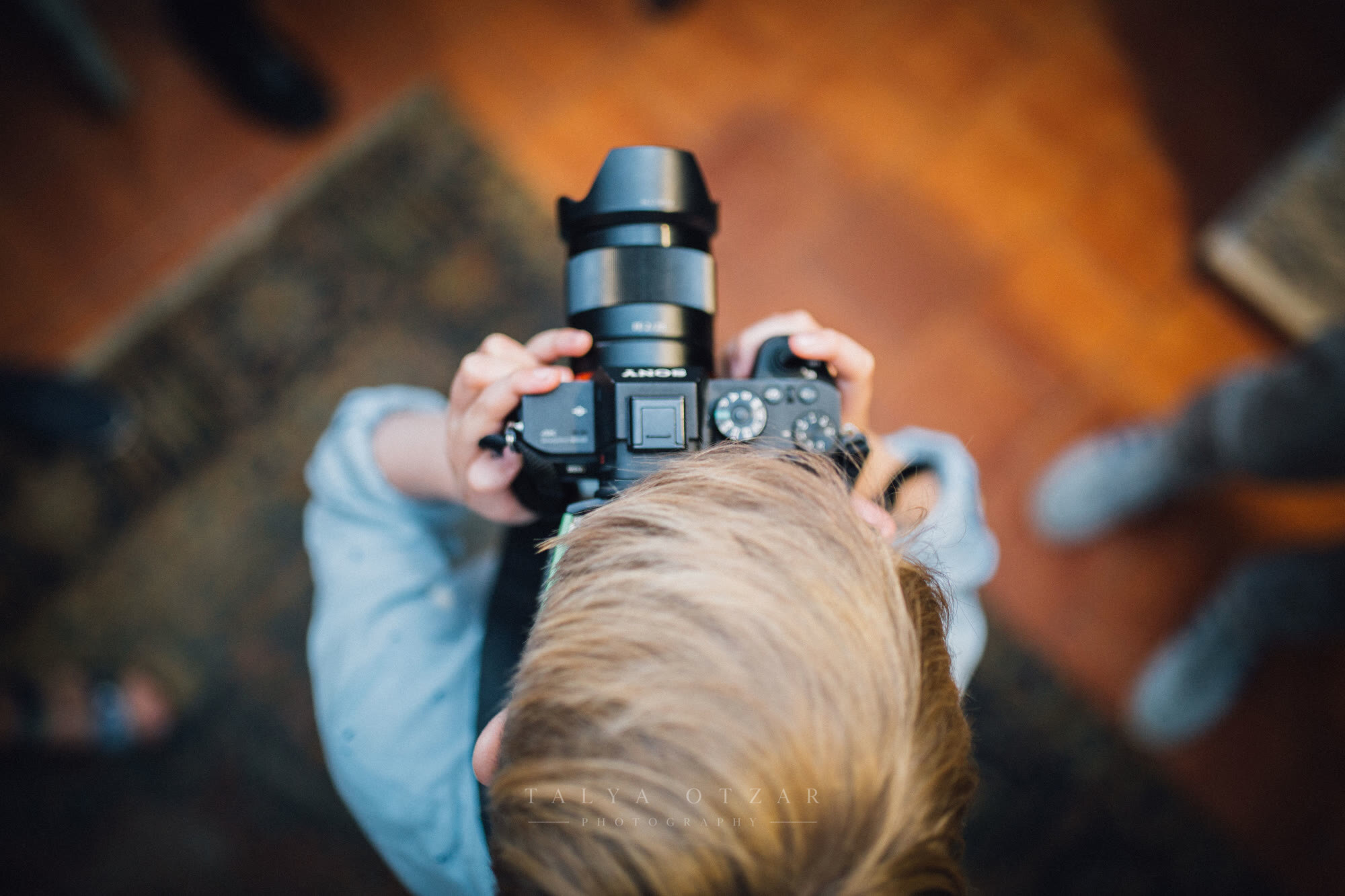 A small child holding a camera up to take a photograph, seen from above
