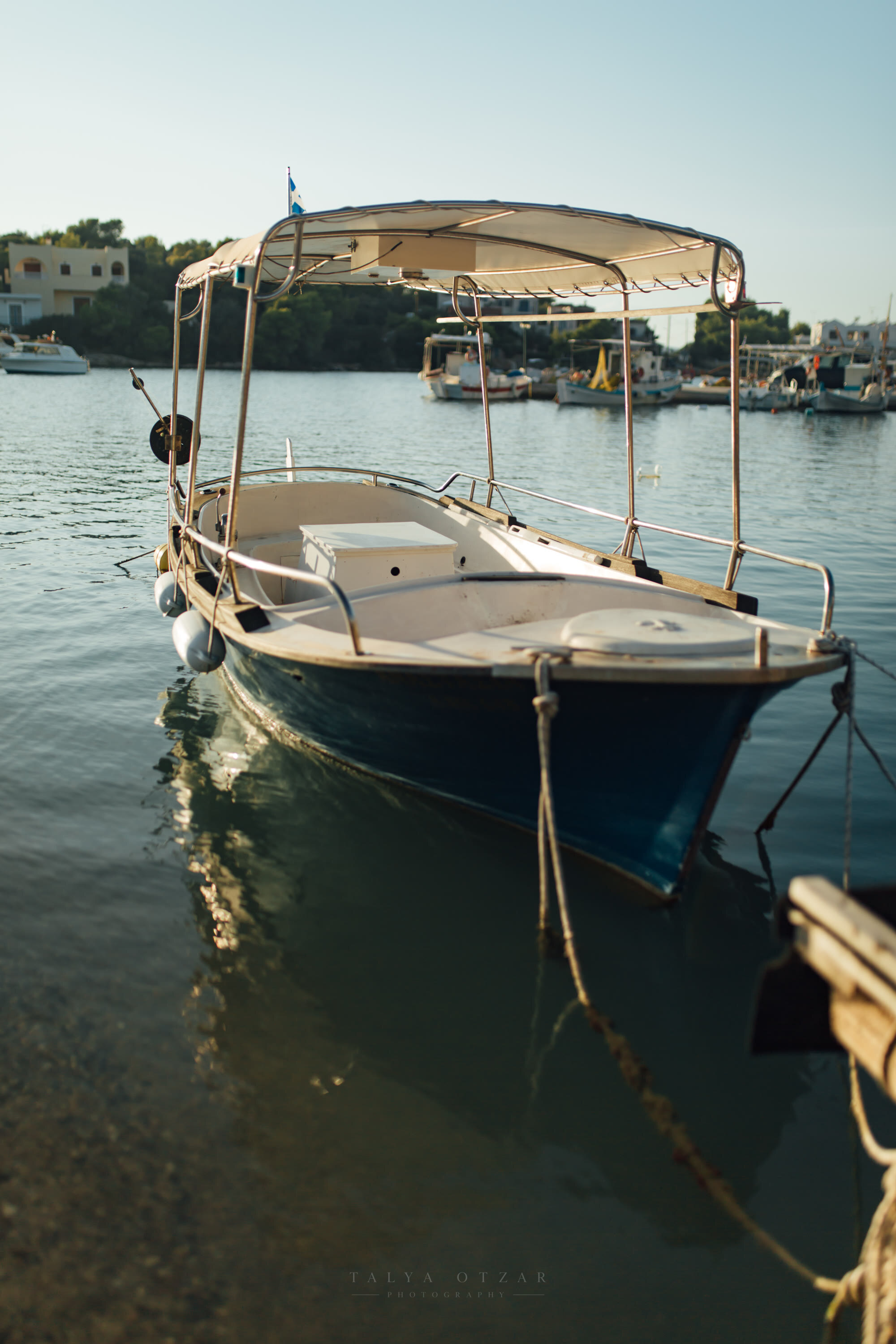 A small boat under a canvas canopy lying still in a Greek harbour