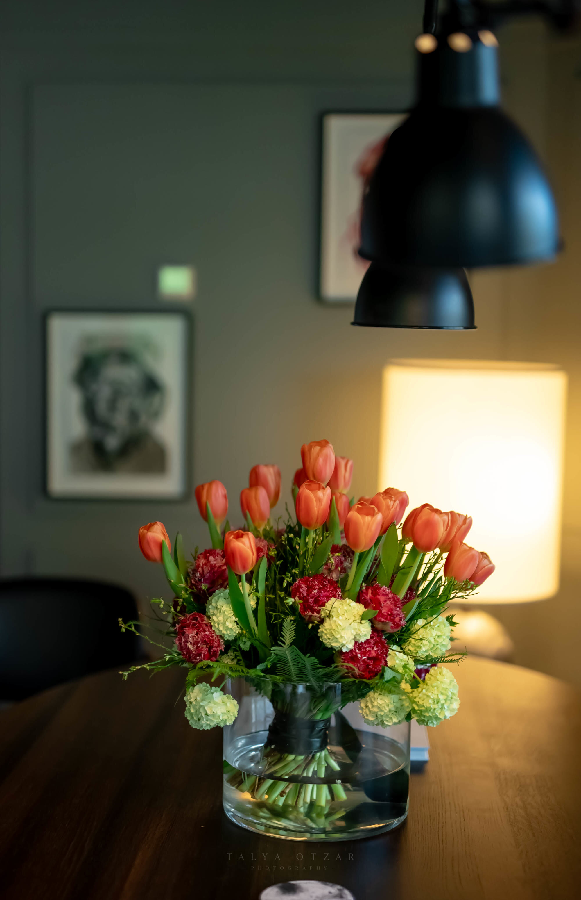 Tulips and carnations in a glass vase on the dining table under a lamp
