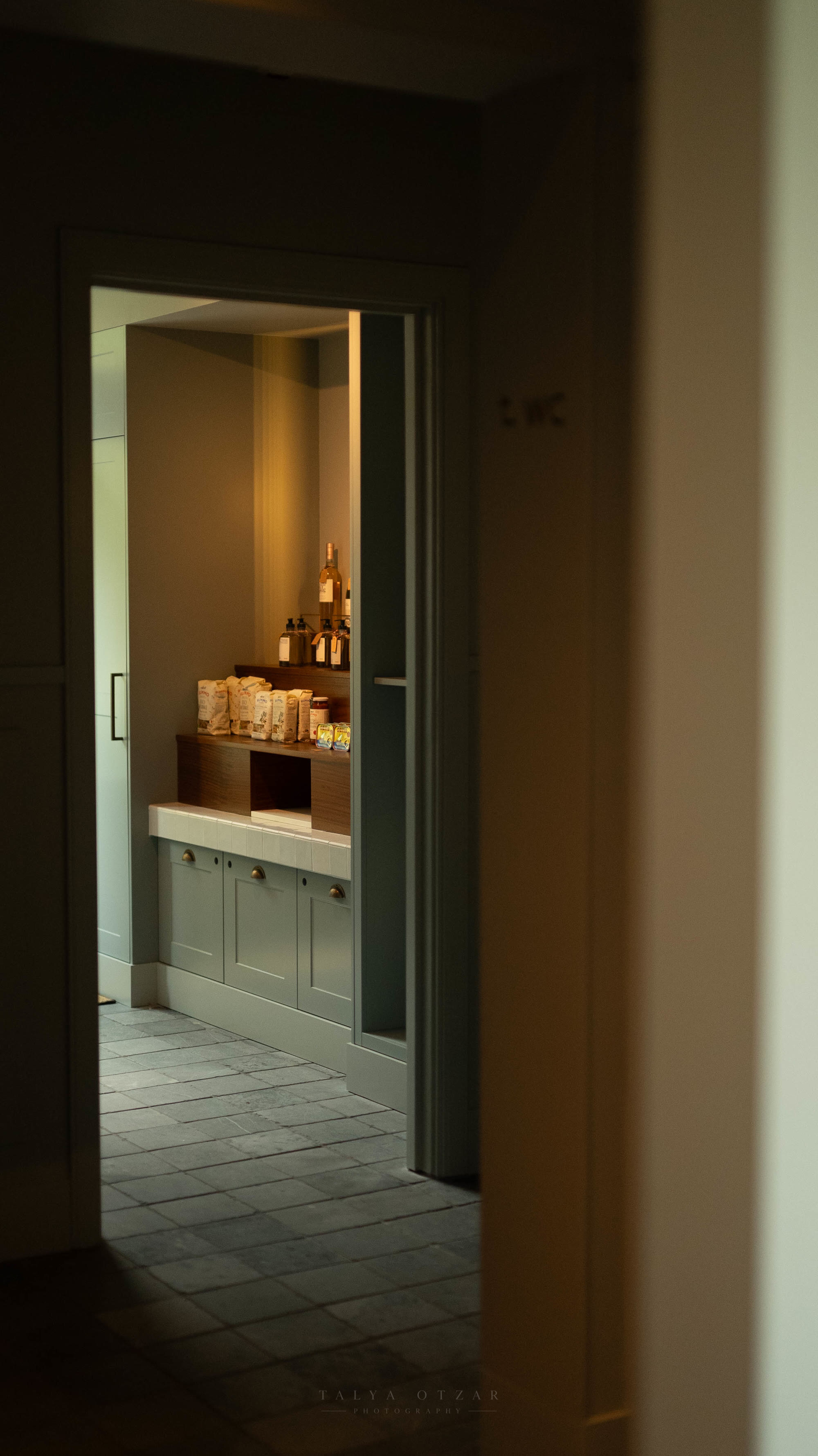 A softly lit pantry glimpsed through an open doorway