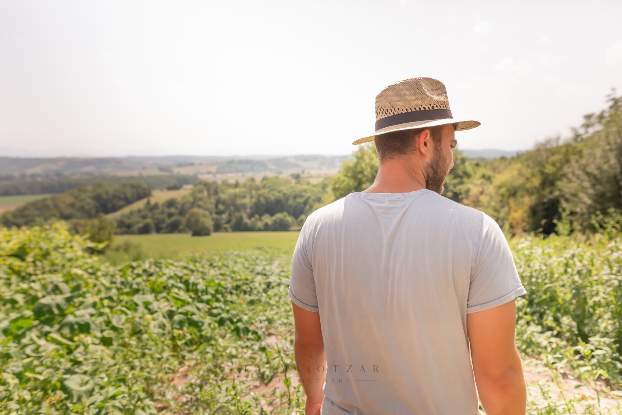 A man in a straw hat looking out over the fields from the edge of the crop