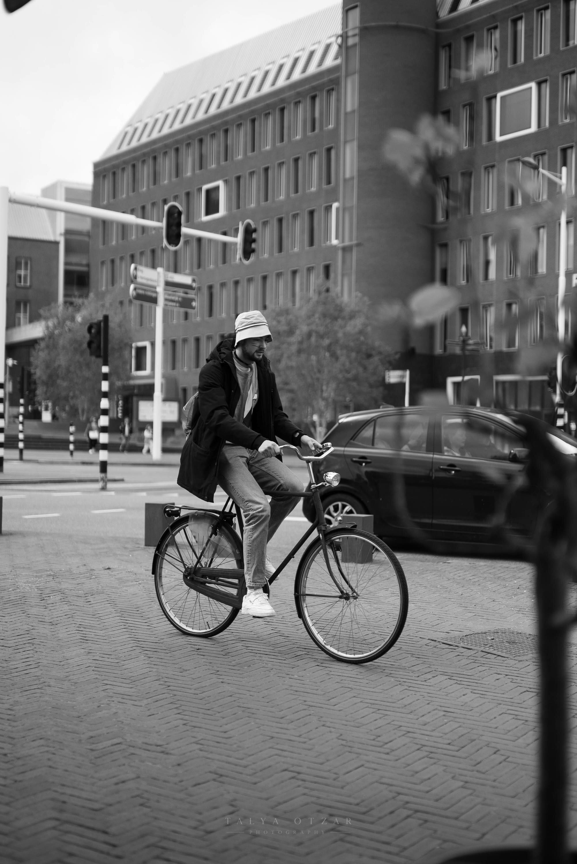 A man cycling across a brick city street past the traffic lights
