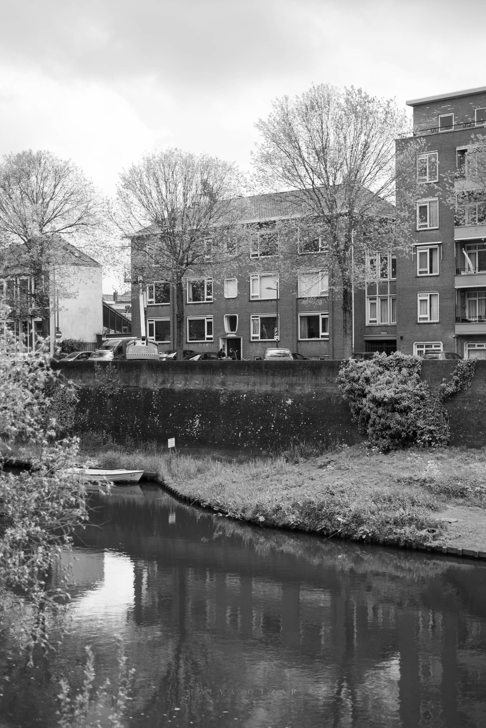 Brick houses along a canal in early spring, a small boat moored below the wall