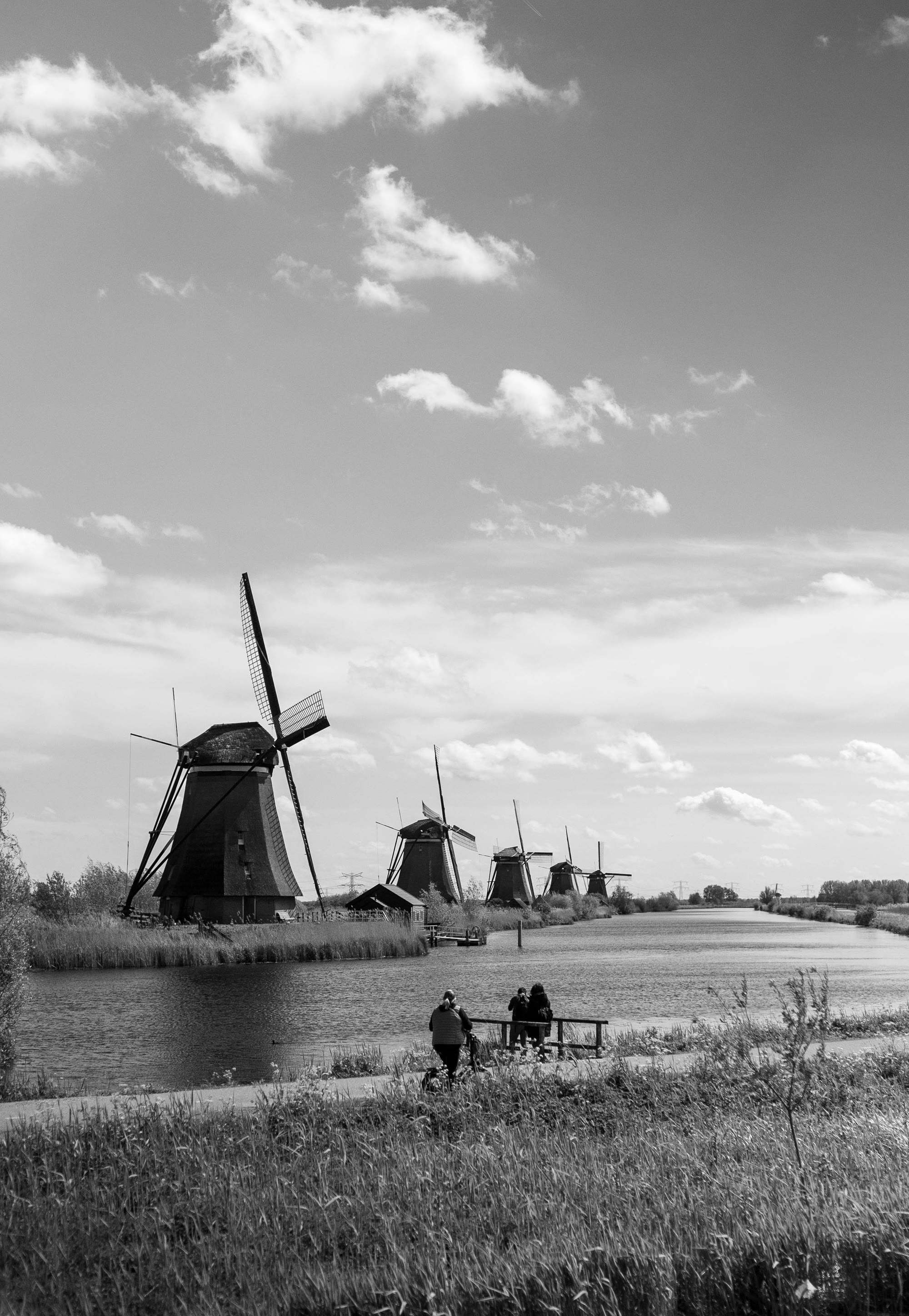 The line of windmills along the canal, walkers small on the path below