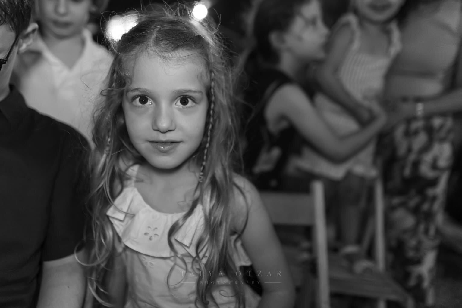 A girl with long hair at an evening party, other children behind her