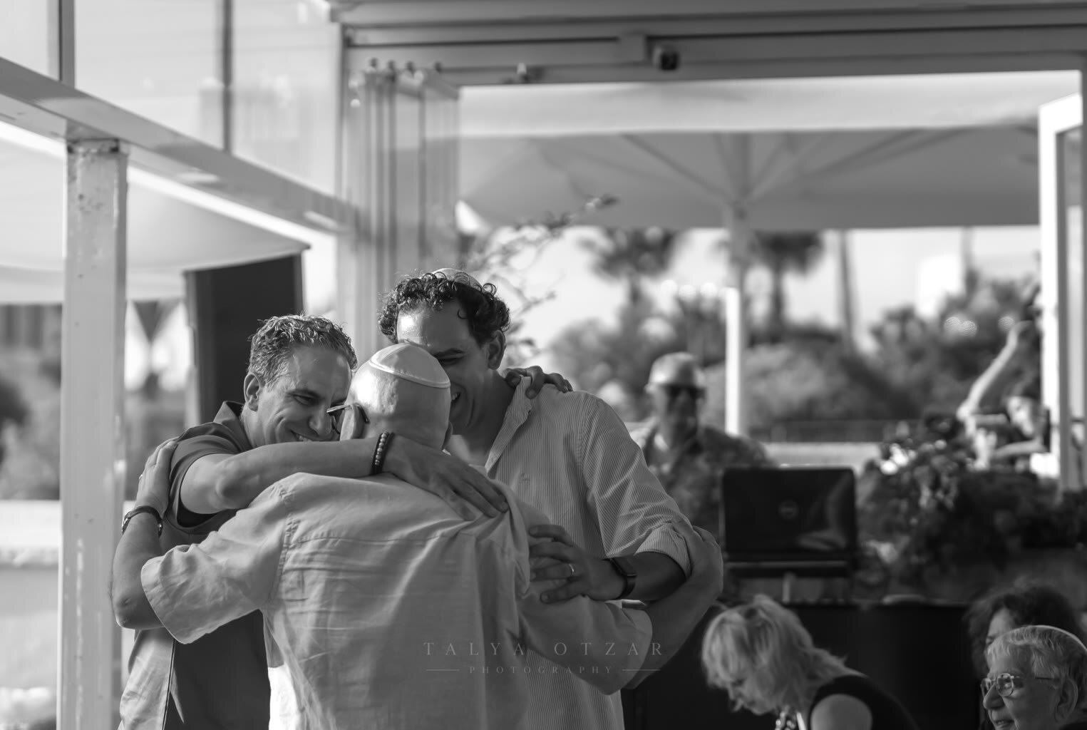 Three men in a long group embrace at the celebration