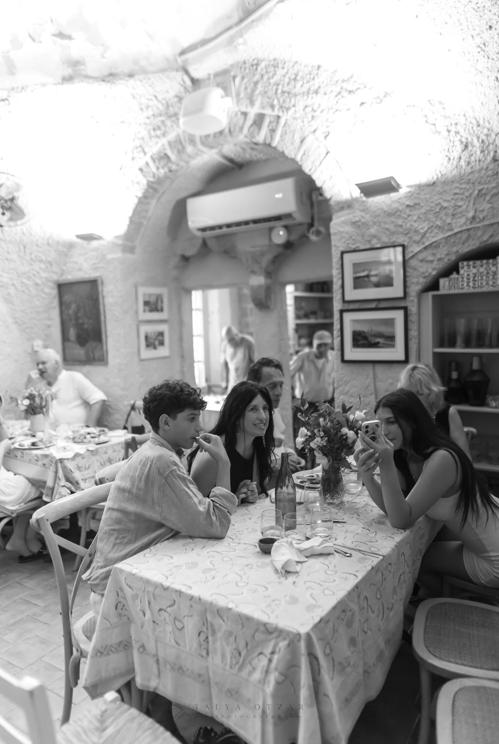 A family around the table in a vaulted stone restaurant, one taking a photograph