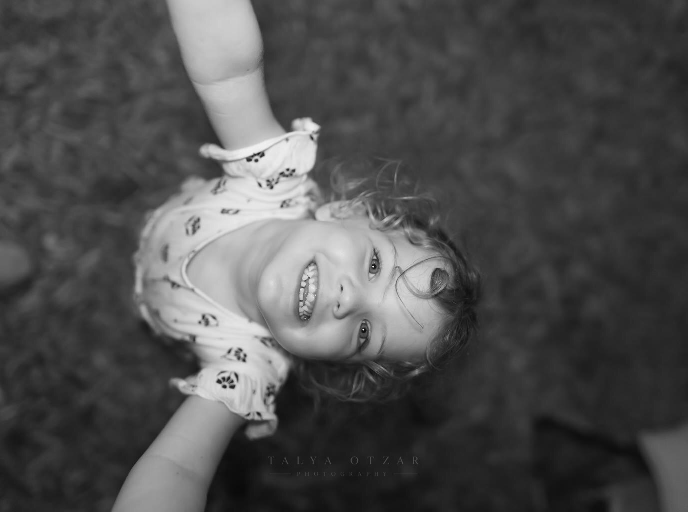 A toddler laughing while being swung by the arms