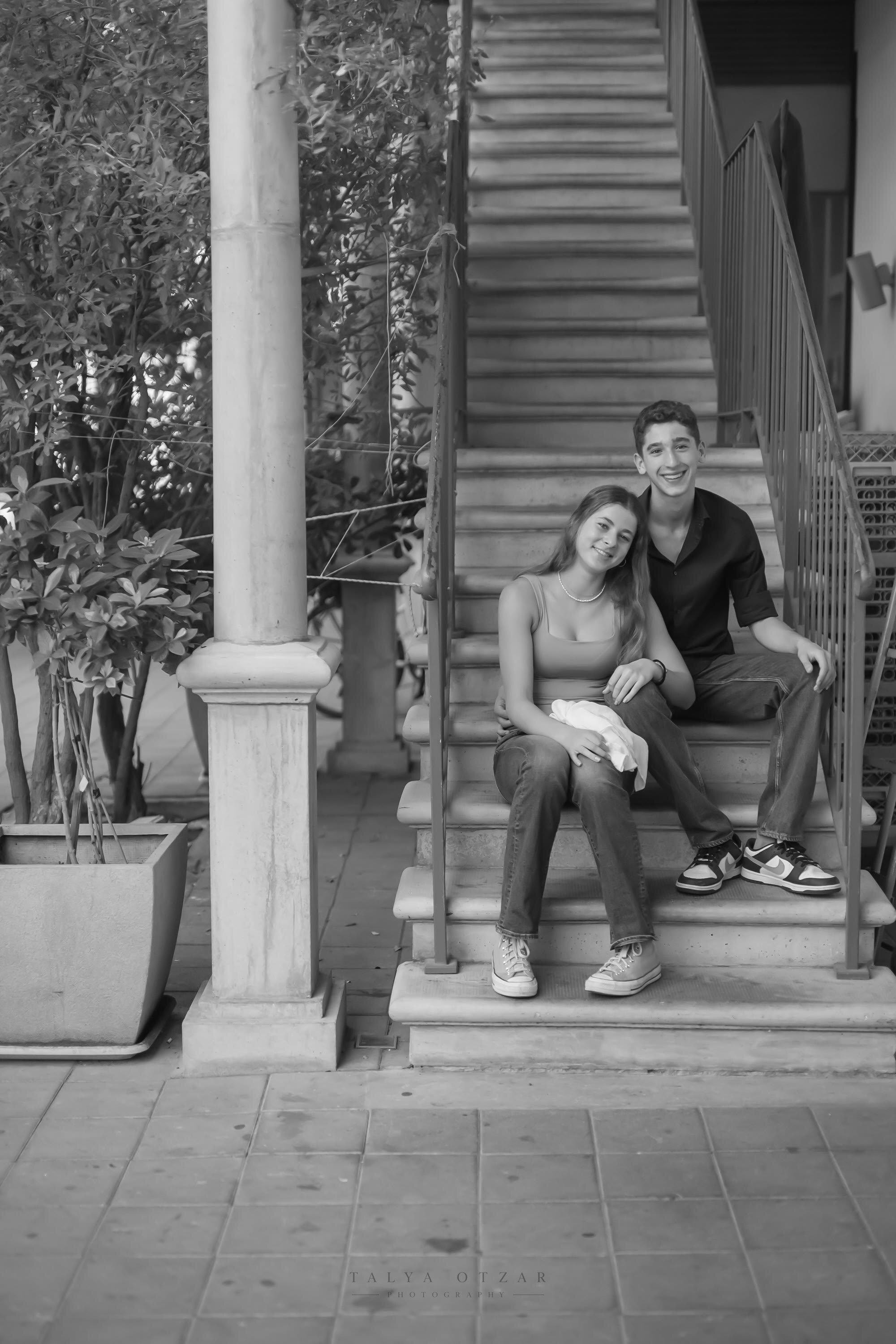 A brother and sister sitting together on the front steps of the house