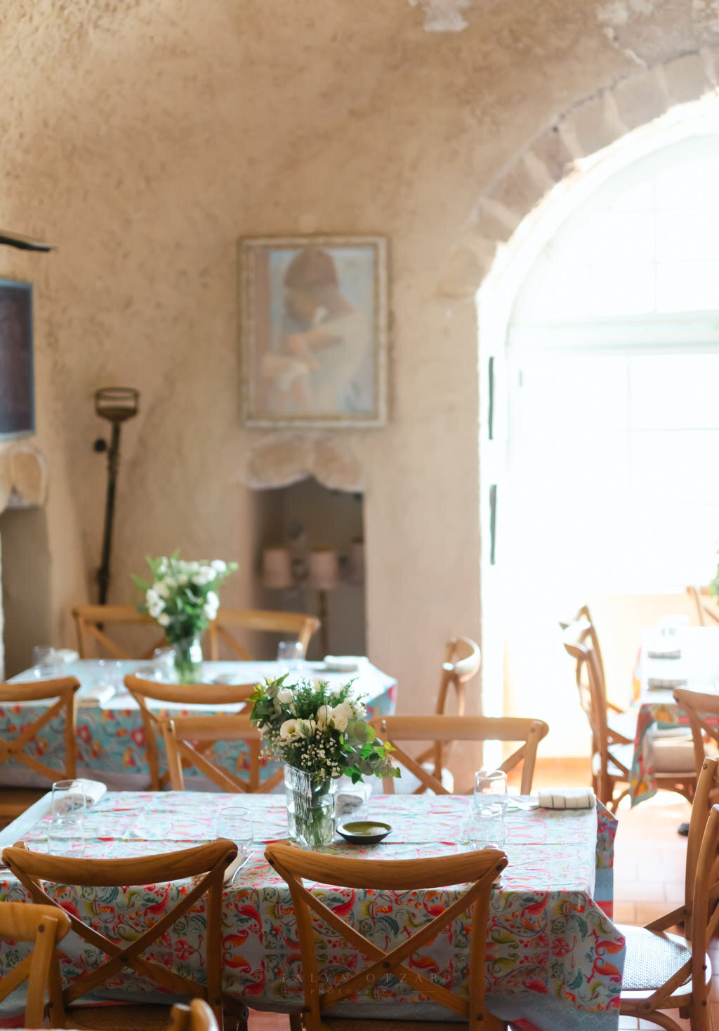 The vaulted stone dining room laid with floral cloths and small vases of flowers