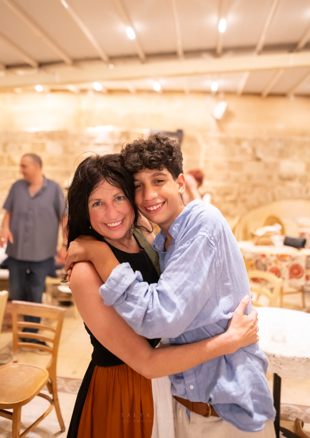 A mother and her teenage son laughing mid-hug at the celebration