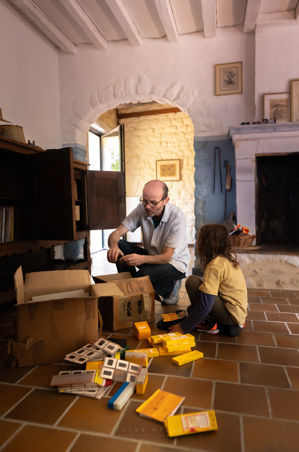 Going through the family slides together by the fireplace, boxes spread across the floor