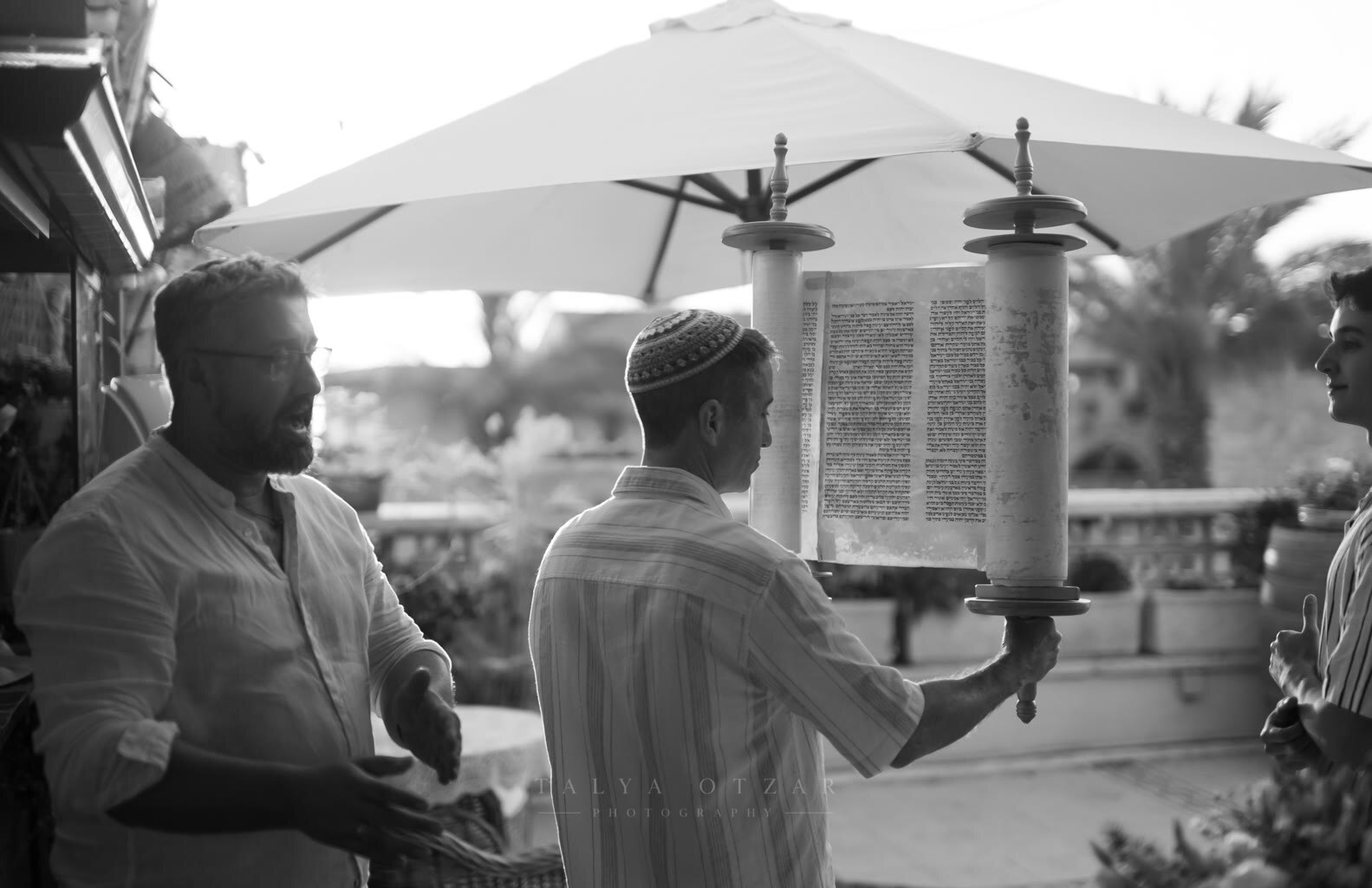A boy holding the open Torah scroll while his father speaks beside him