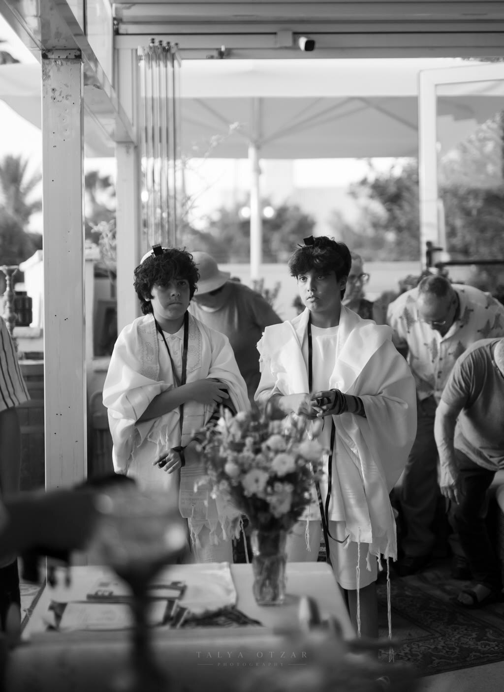 Two boys in prayer shawls waiting together at the bar mitzvah celebration