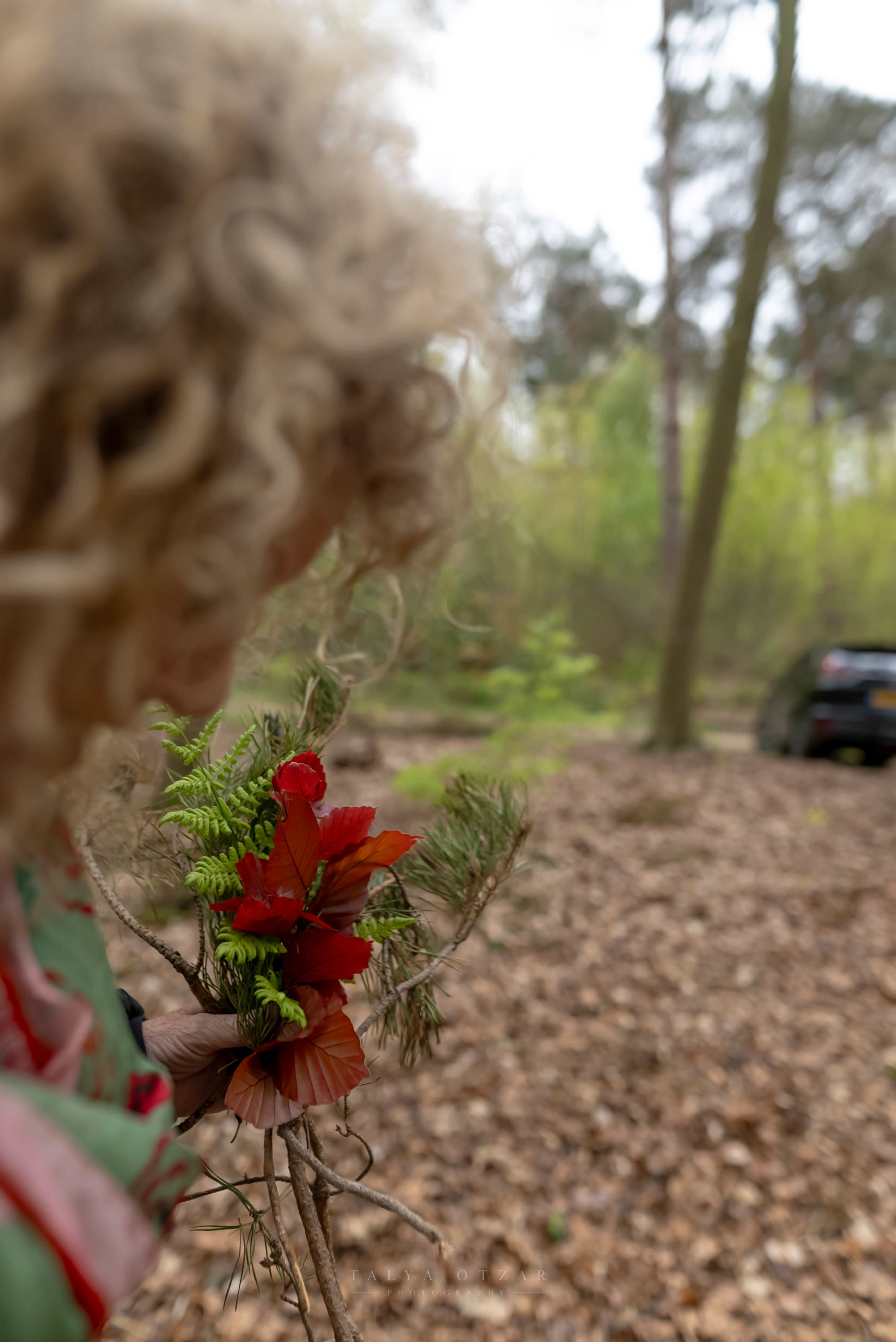 A child holding up the bunch of leaves and ferns they gathered in the forest