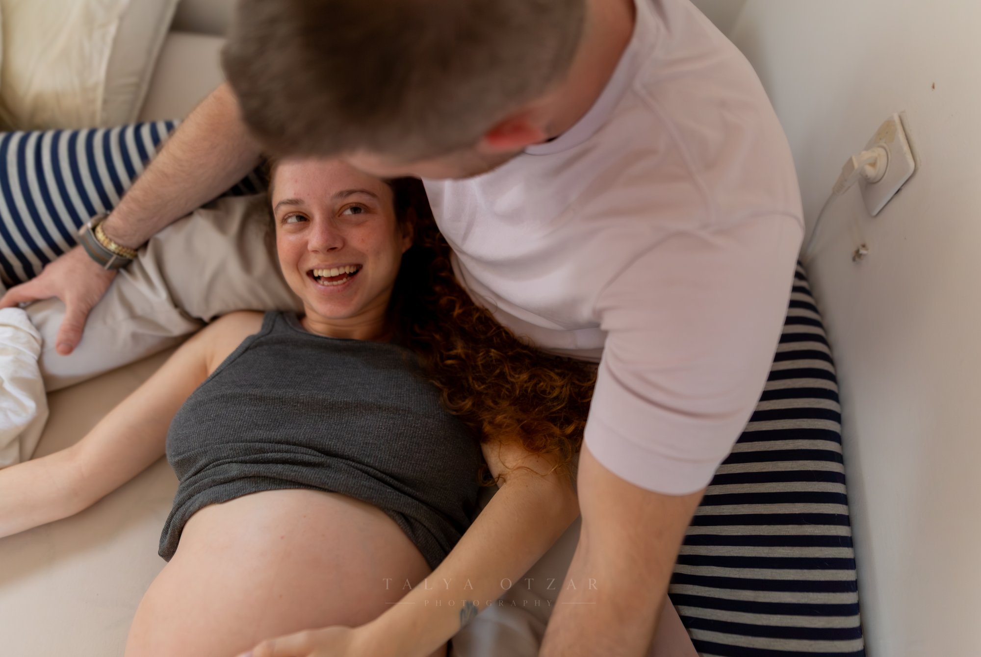 סיגי צוחקת על הספה בזמן שלוטם רוכן מעליה, צילום מלמעלה