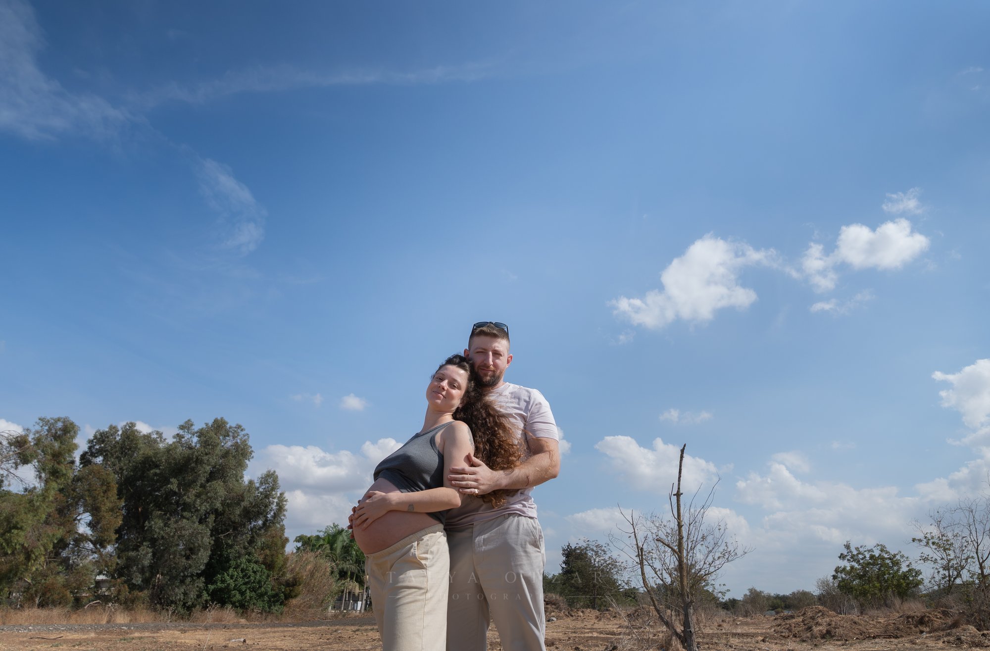 לוטם מחבק את סיגי מאחור תחת שמיים כחולים ופתוחים