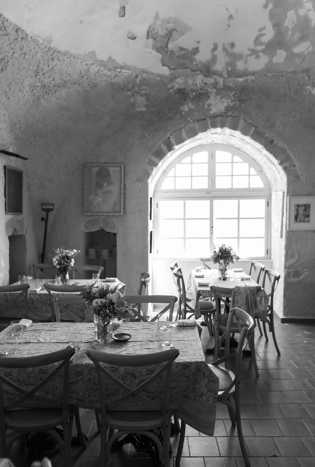 The vaulted stone dining room laid for the wedding meal, light pouring through a tall arched window