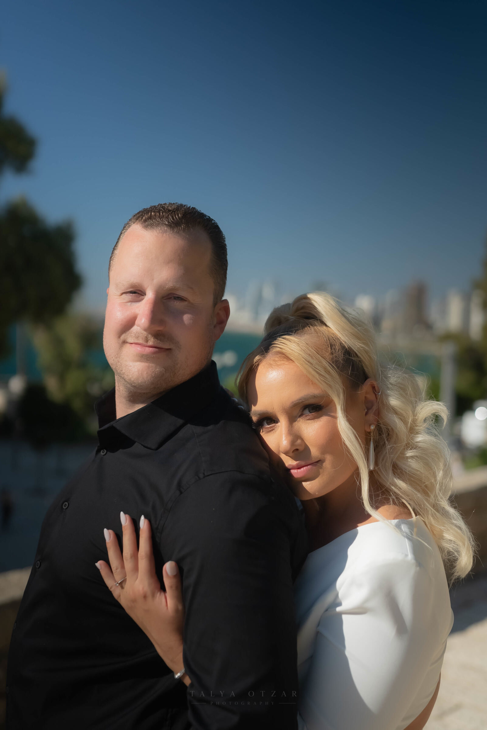 Close portrait of the couple with the Tel Aviv skyline soft behind them