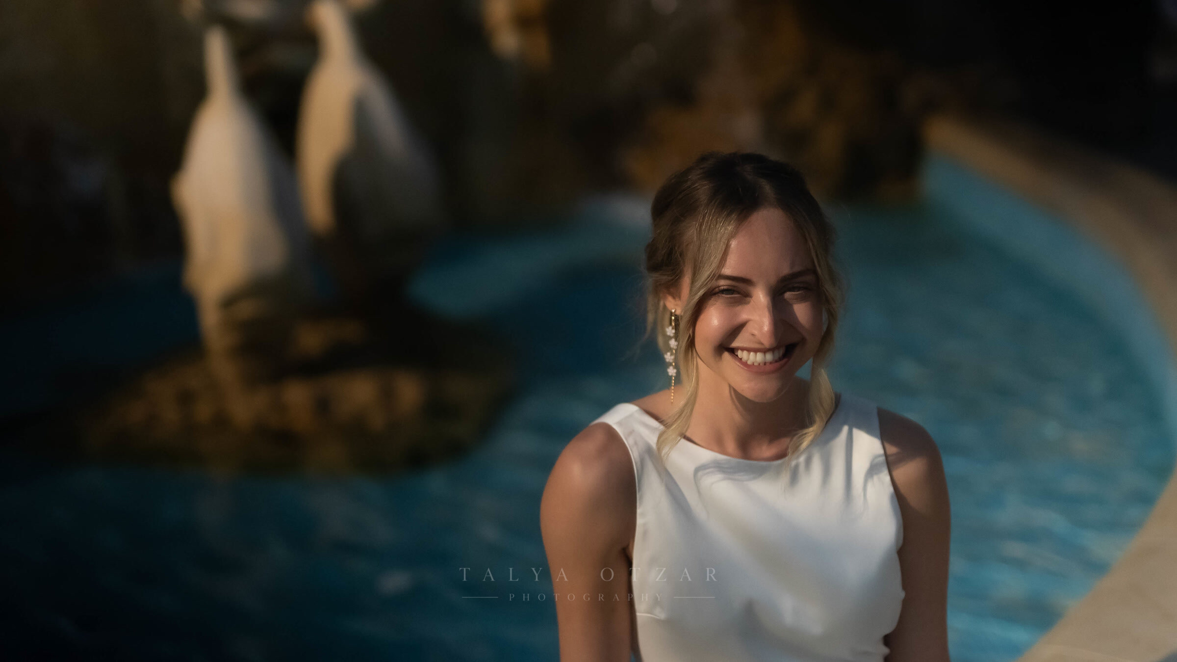 The bride laughing beside a floodlit pool as the light goes