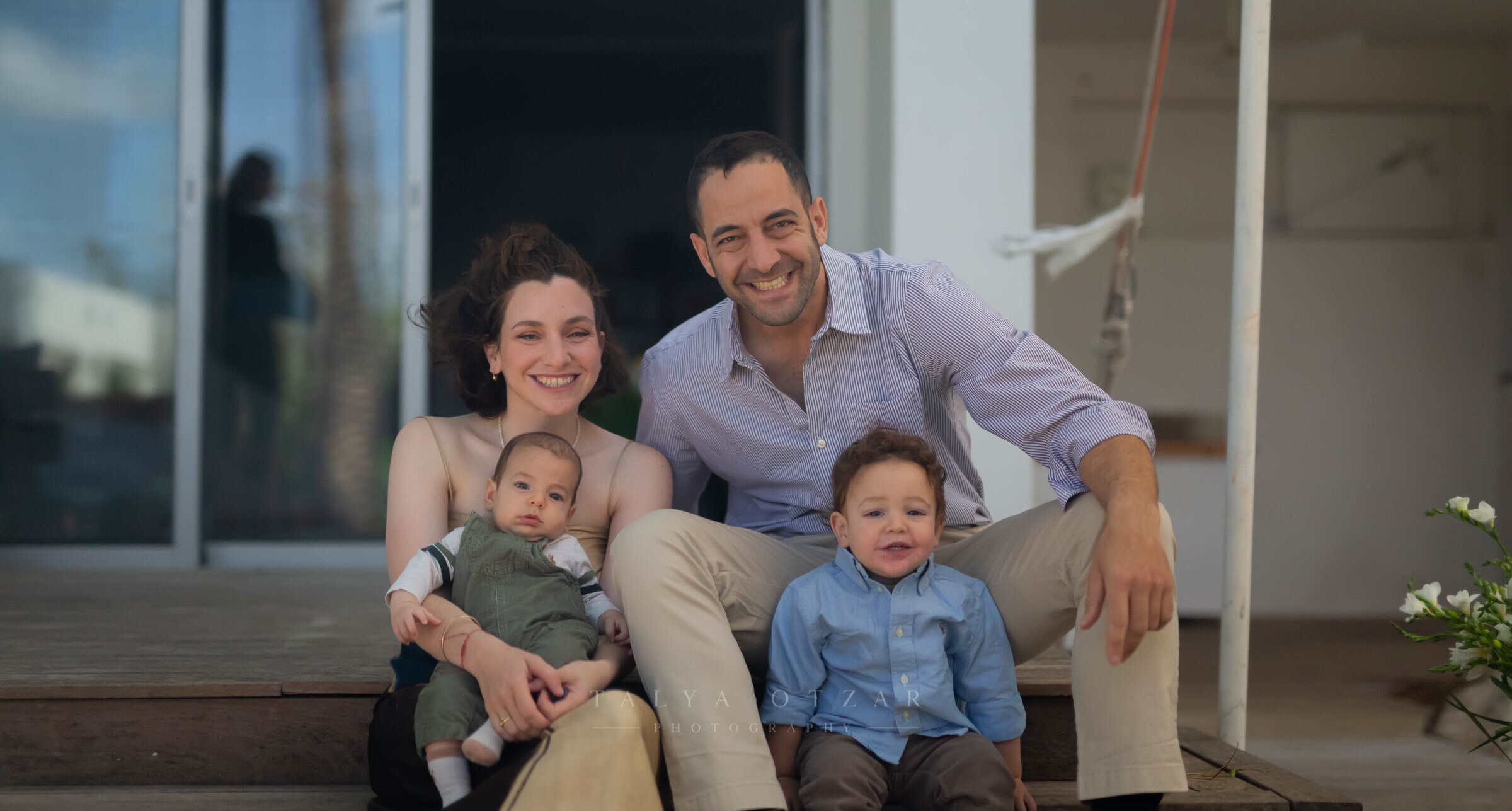 Parents sitting on the step of a house with their baby and toddler
