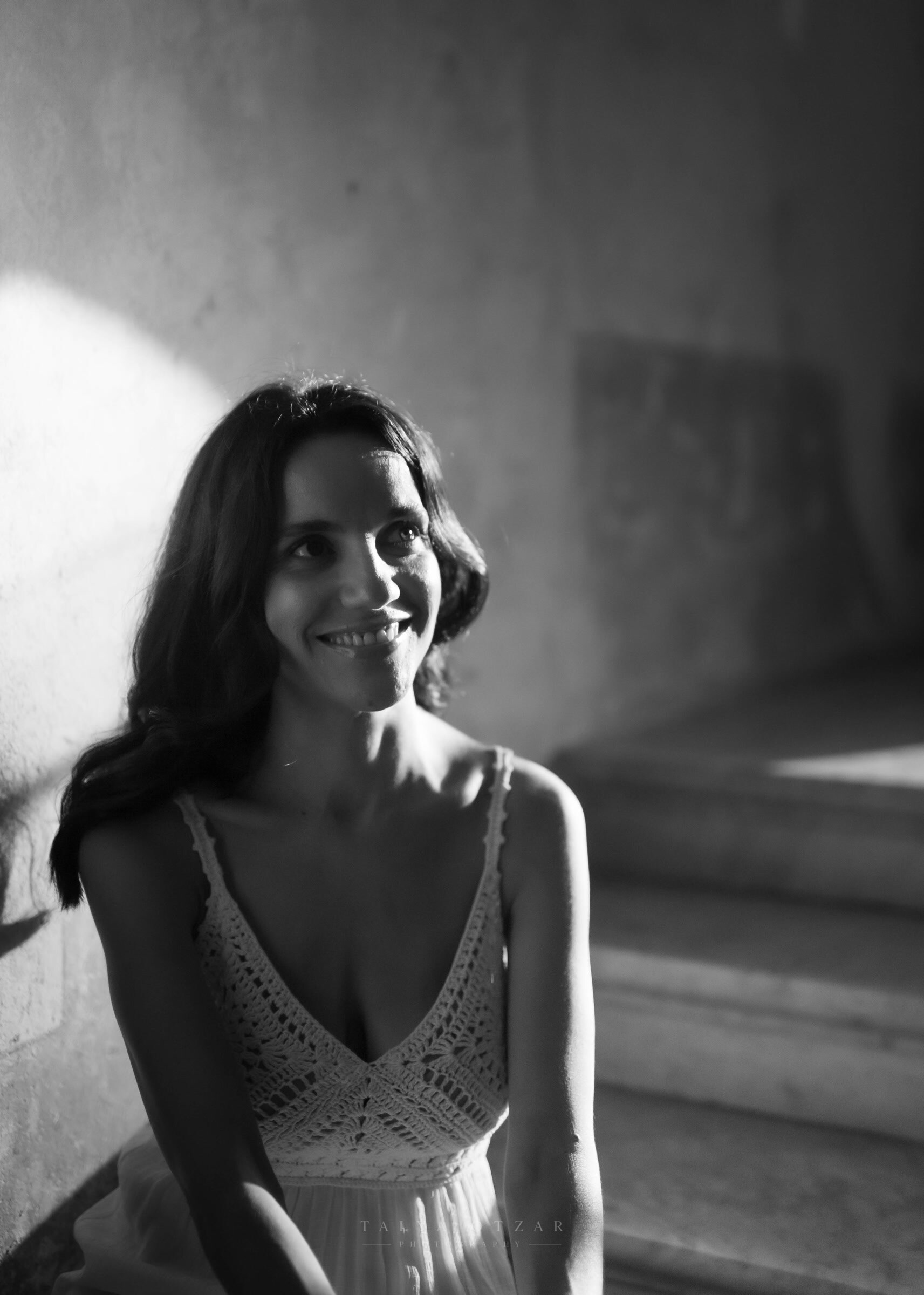 A guest smiling in a shaft of light on the stone steps