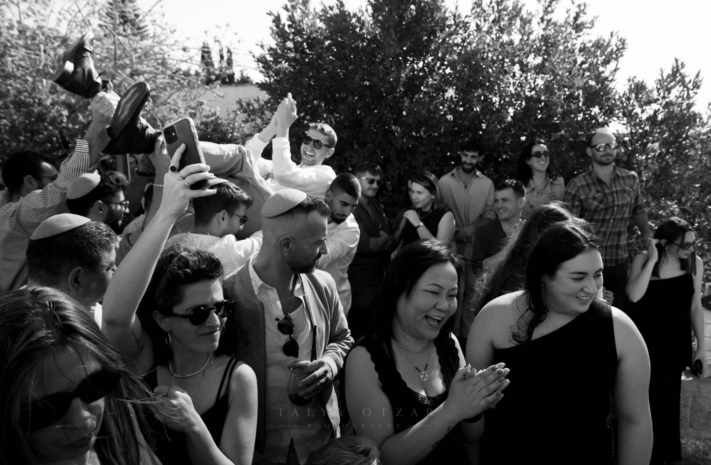 Guests laughing and clapping as someone is lifted on shoulders behind them