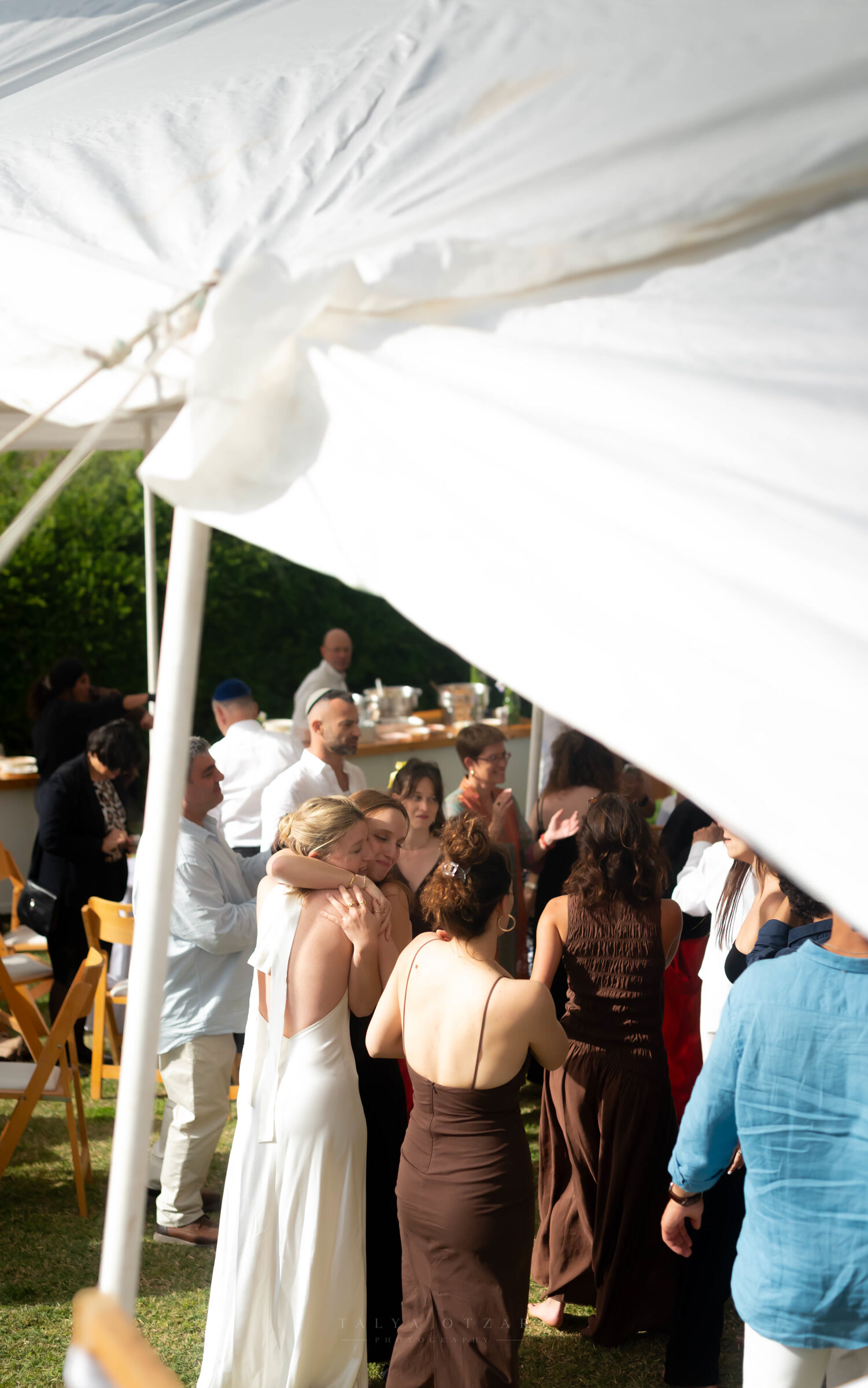 The bride holding a guest close under the billowing white marquee