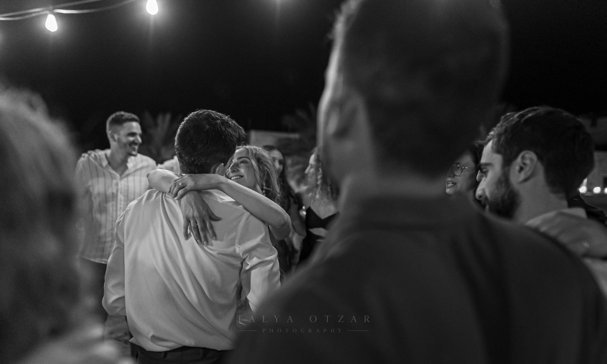 Guests holding each other on the dance floor beneath the festoon lights