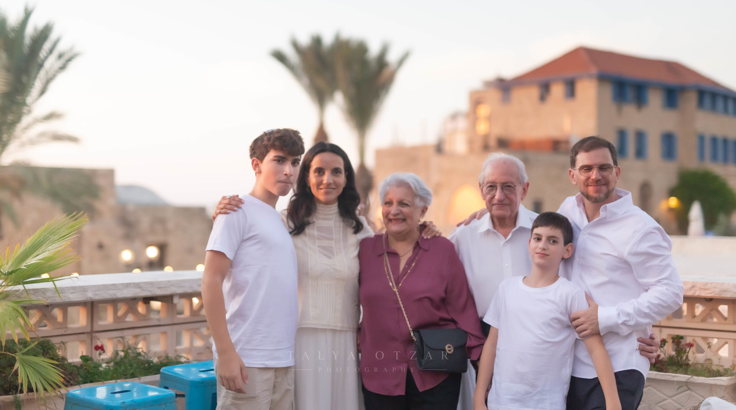 Three generations of one family photographed together on the Jaffa rooftop at dusk