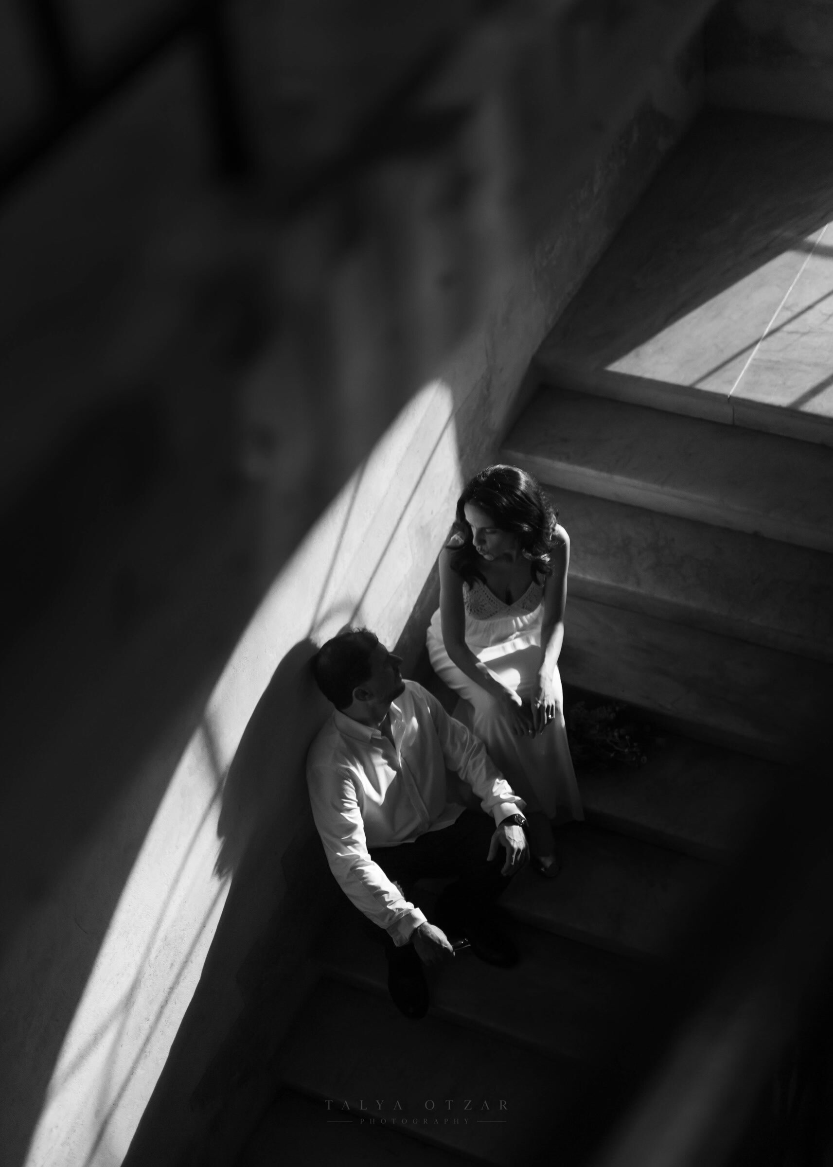 The couple sitting together on a stone staircase in a shaft of afternoon light