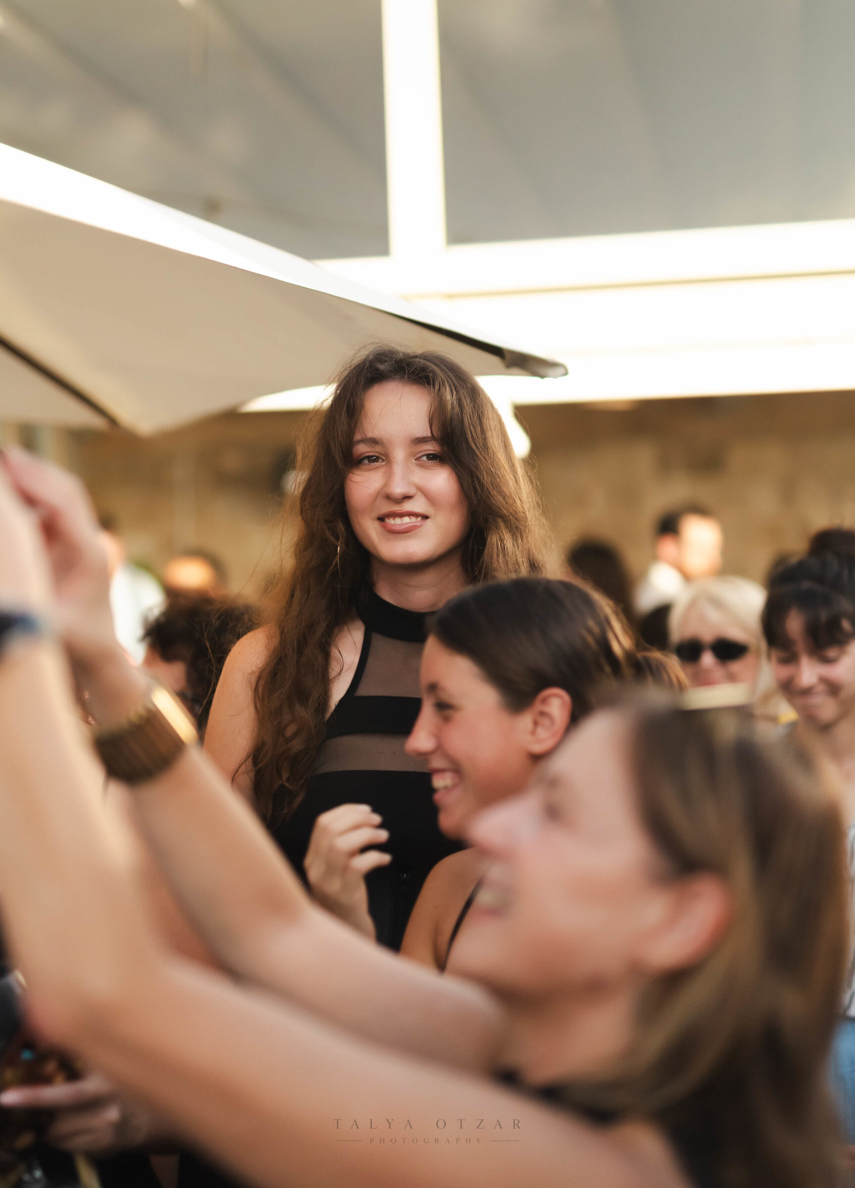 A guest smiling among friends as glasses are raised around her