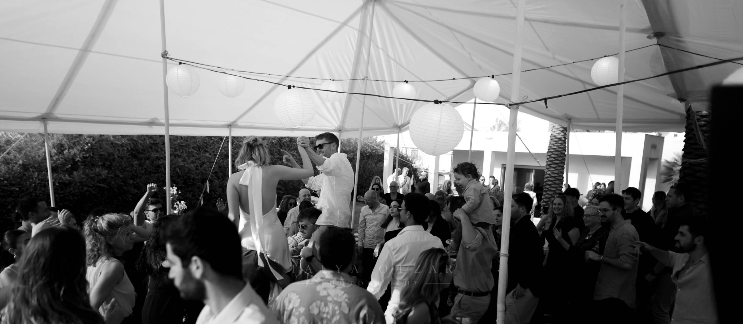 The crowded dance floor under the marquee, bride and groom somewhere in the middle of it