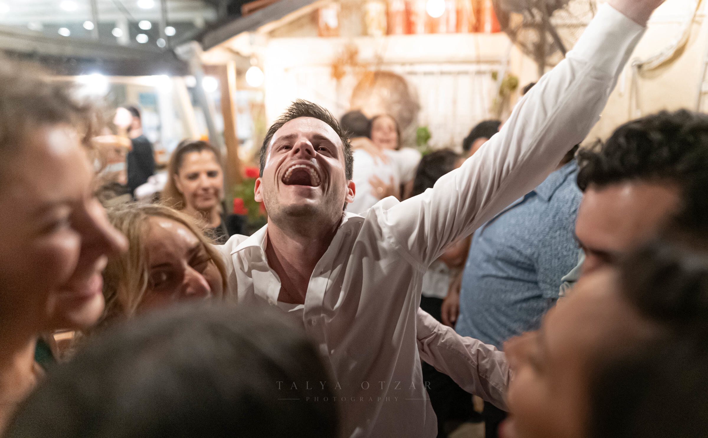 A guest throwing his head back laughing, one arm raised on the dance floor