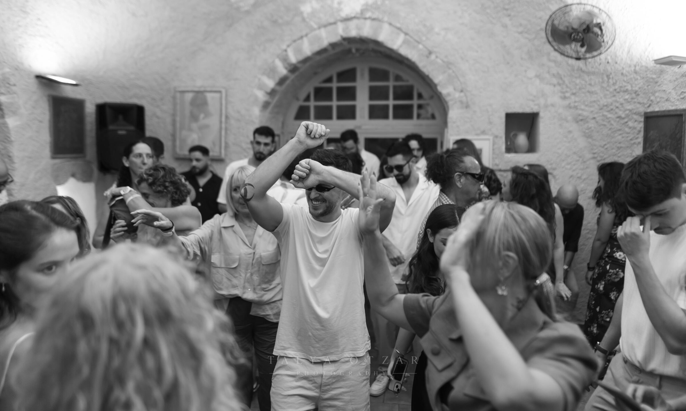 The dance floor filling the vaulted stone hall, one guest dancing with arms raised