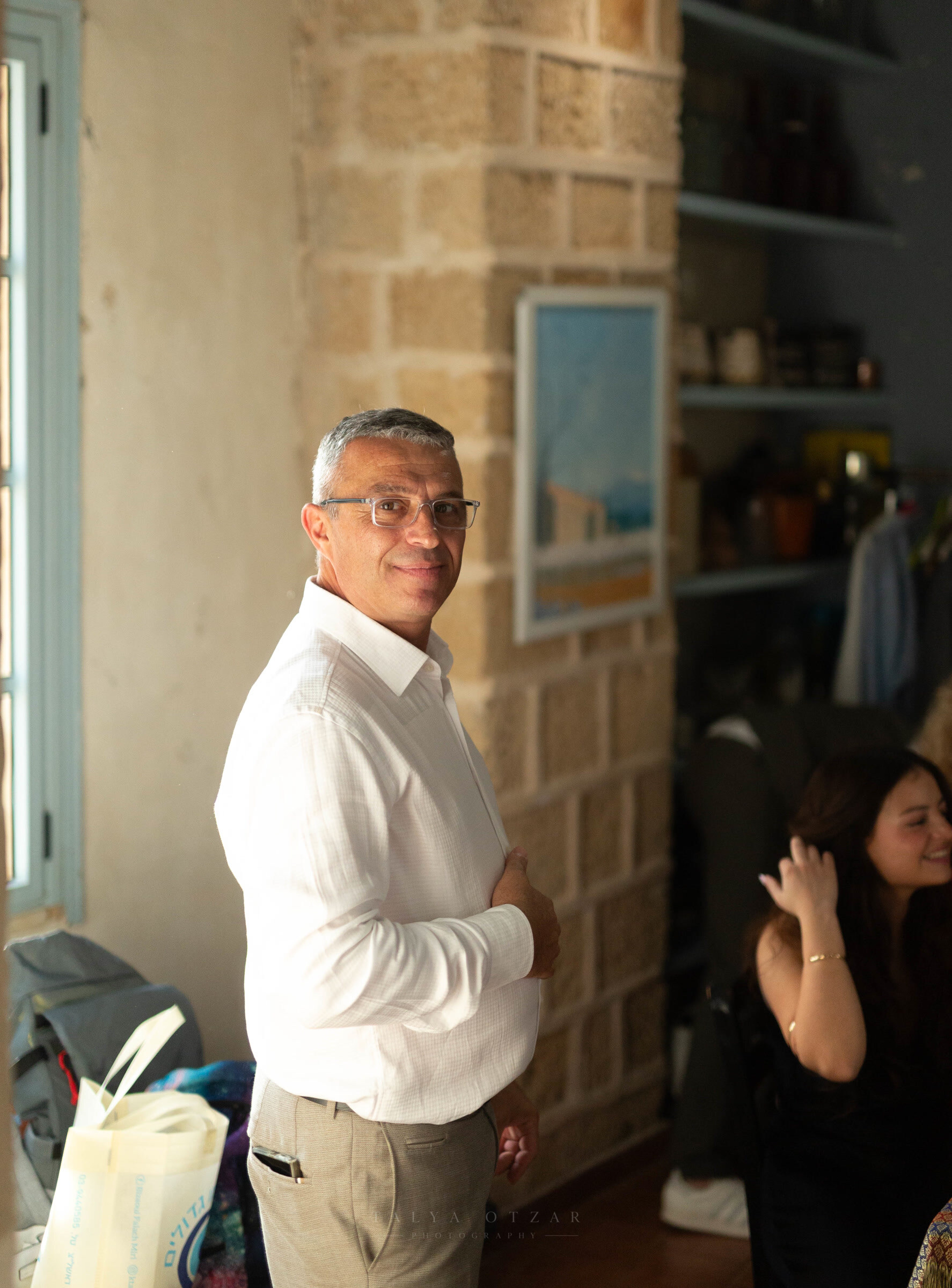 A guest smiling over his shoulder in the stone-walled room, a seascape hanging behind him