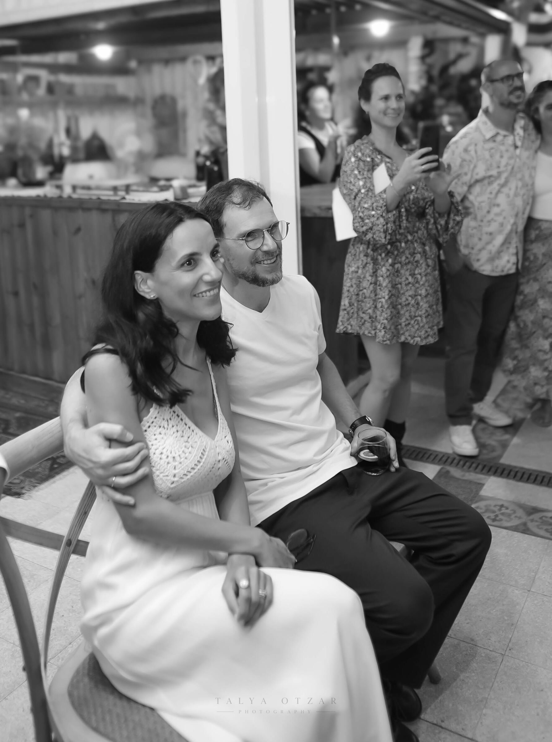 A couple among the guests posing together for a photograph at the reception