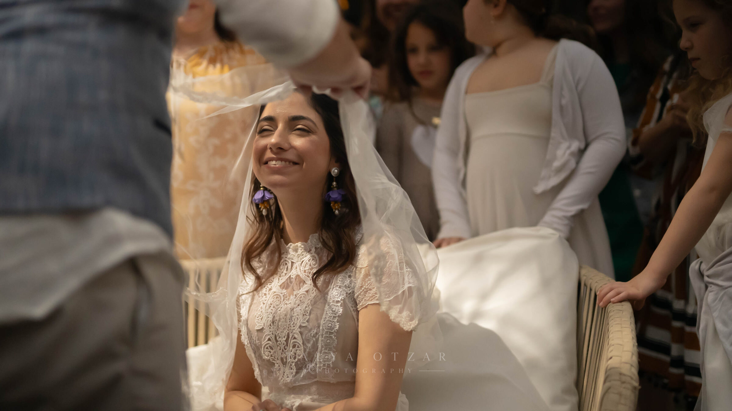 The veiled bride smiling up at someone, girls in cream dresses standing behind her