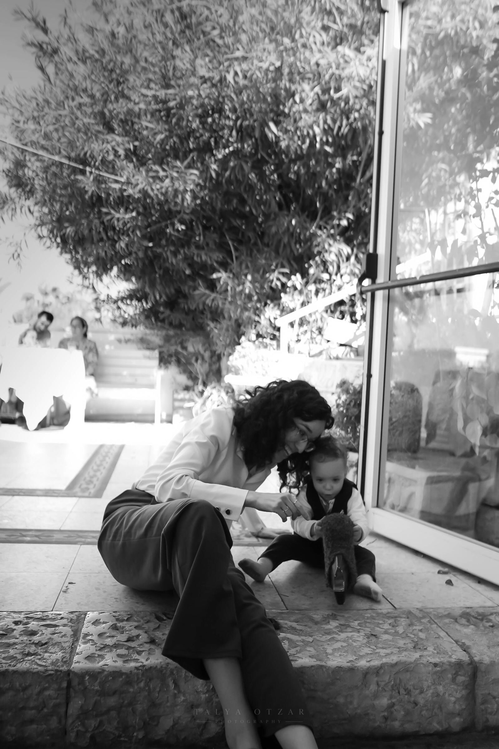 A guest sitting on the step playing with a toddler outside the glass doors