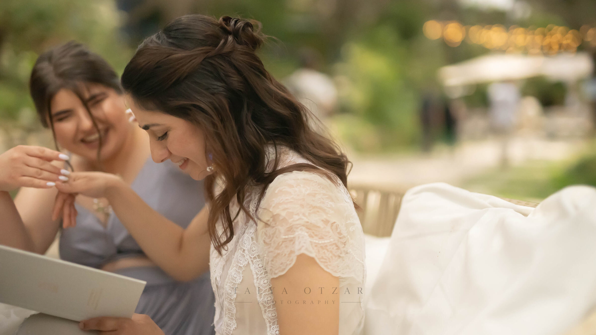 The bride laughing while a friend helps her get ready in the garden
