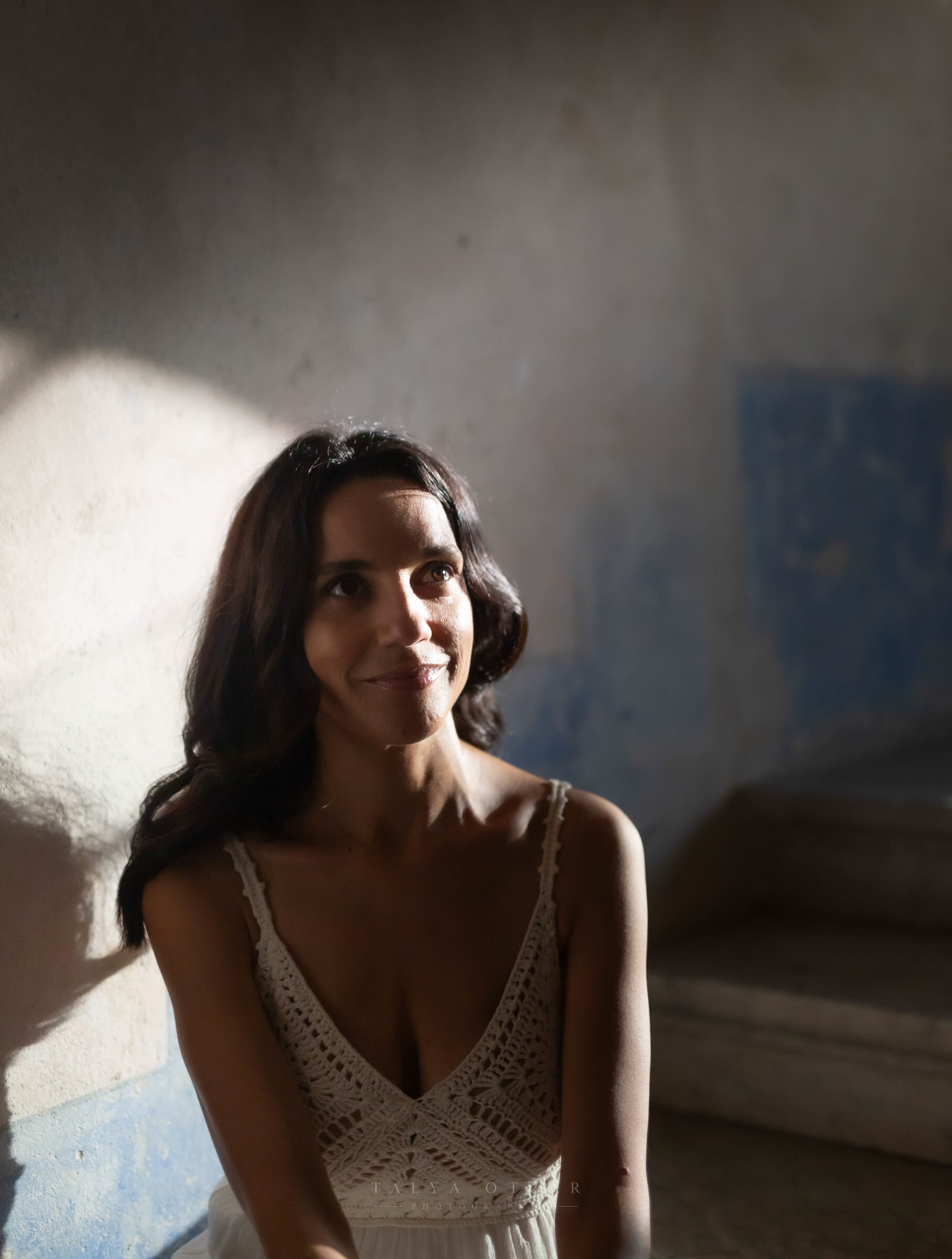 A guest smiling in soft light against a blue-washed wall
