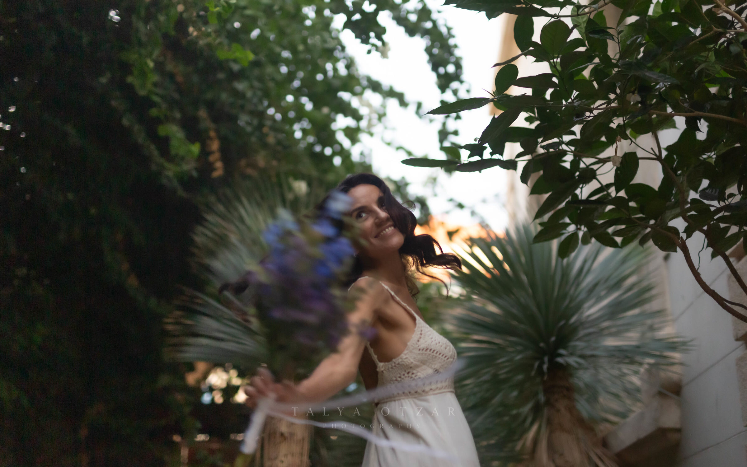 The bride spinning in the garden with her bouquet, the movement blurring the frame