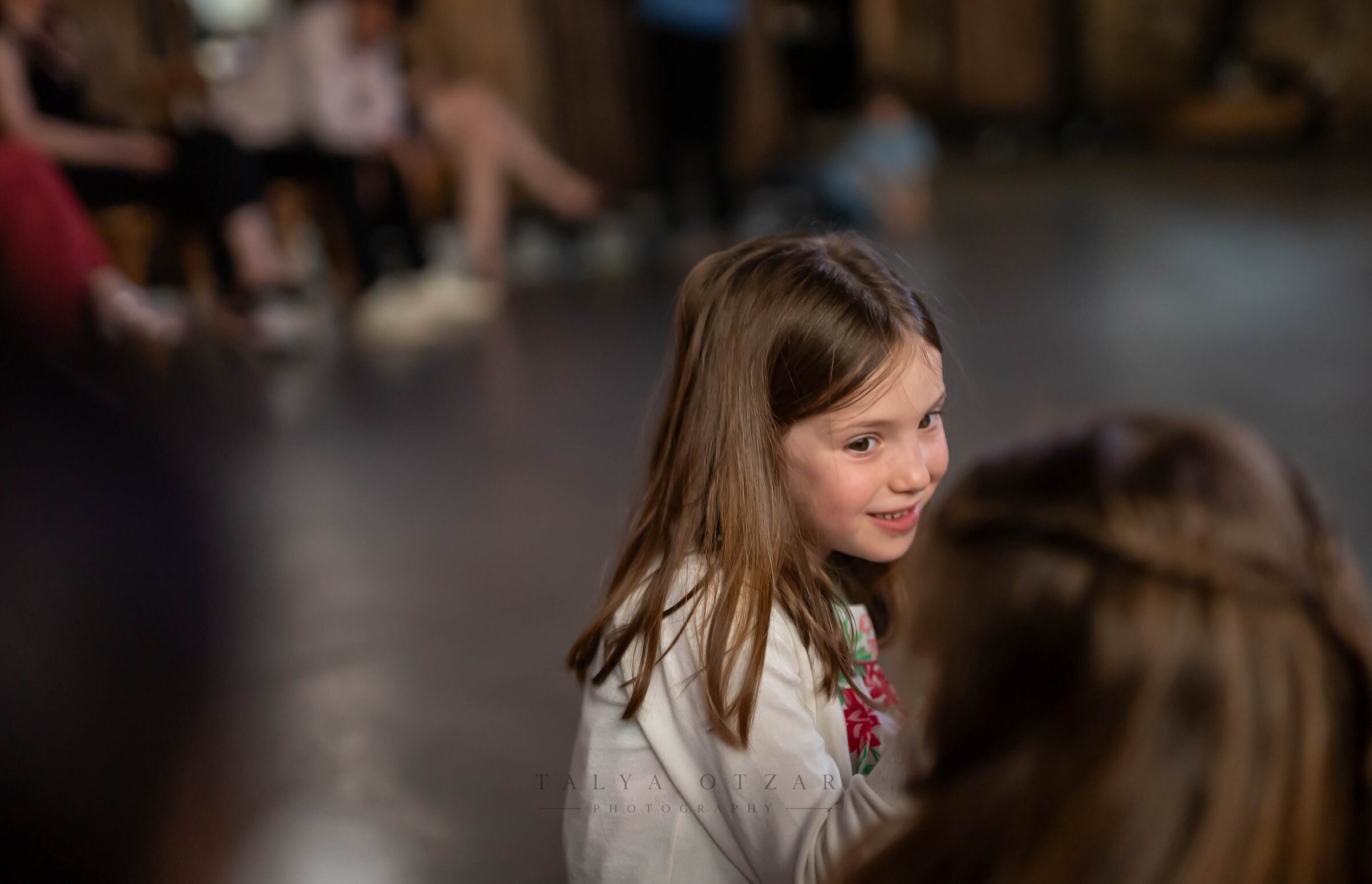 A young guest smiling on the edge of the dance floor