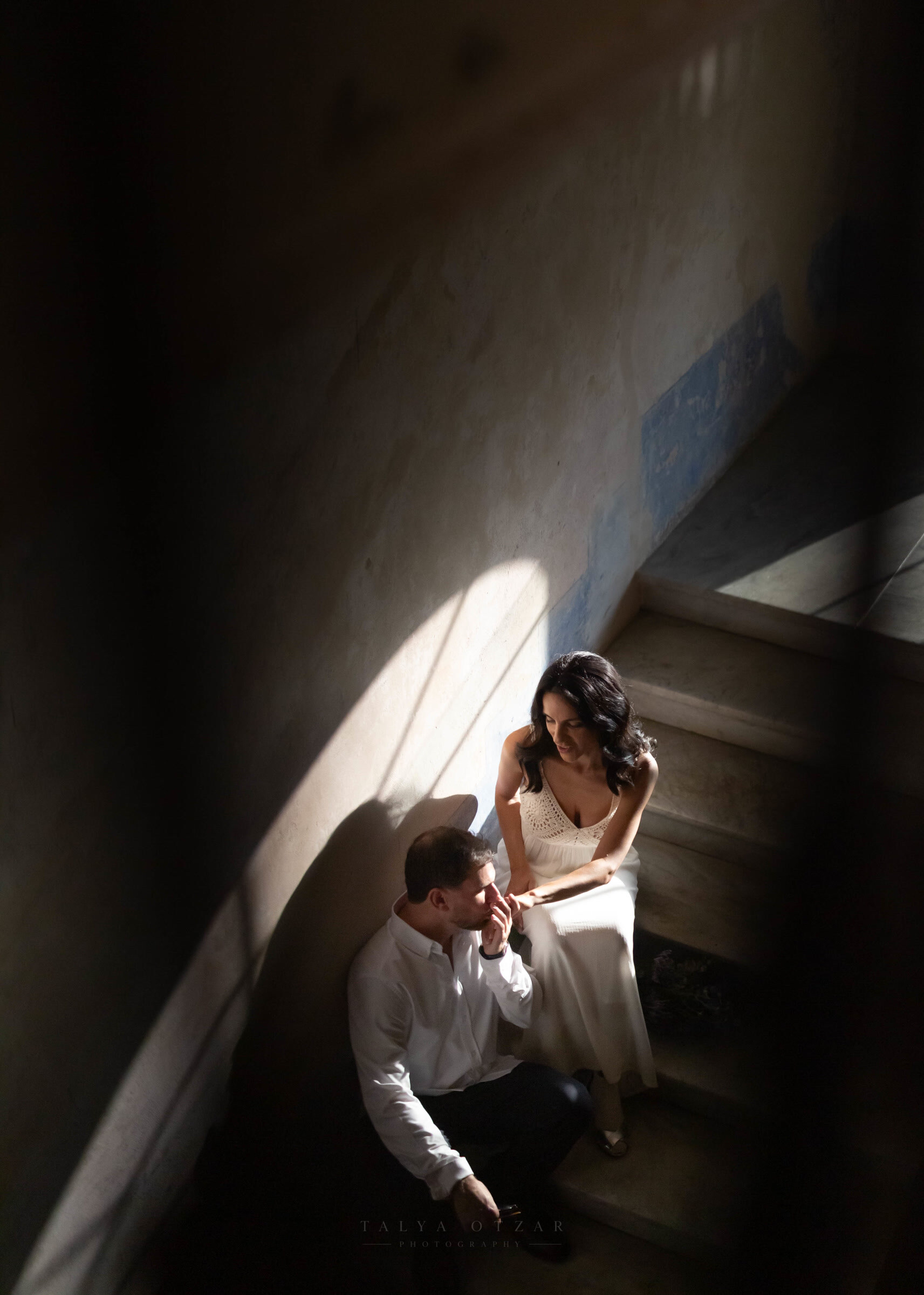 The groom kissing the bride's hand on the stone stairs, photographed from above