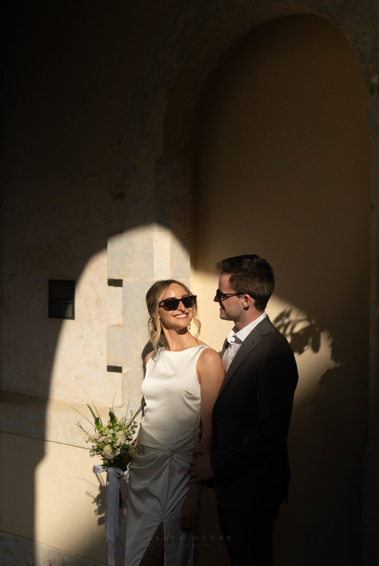 The couple looking at each other in the low sun, the bride holding a white bouquet