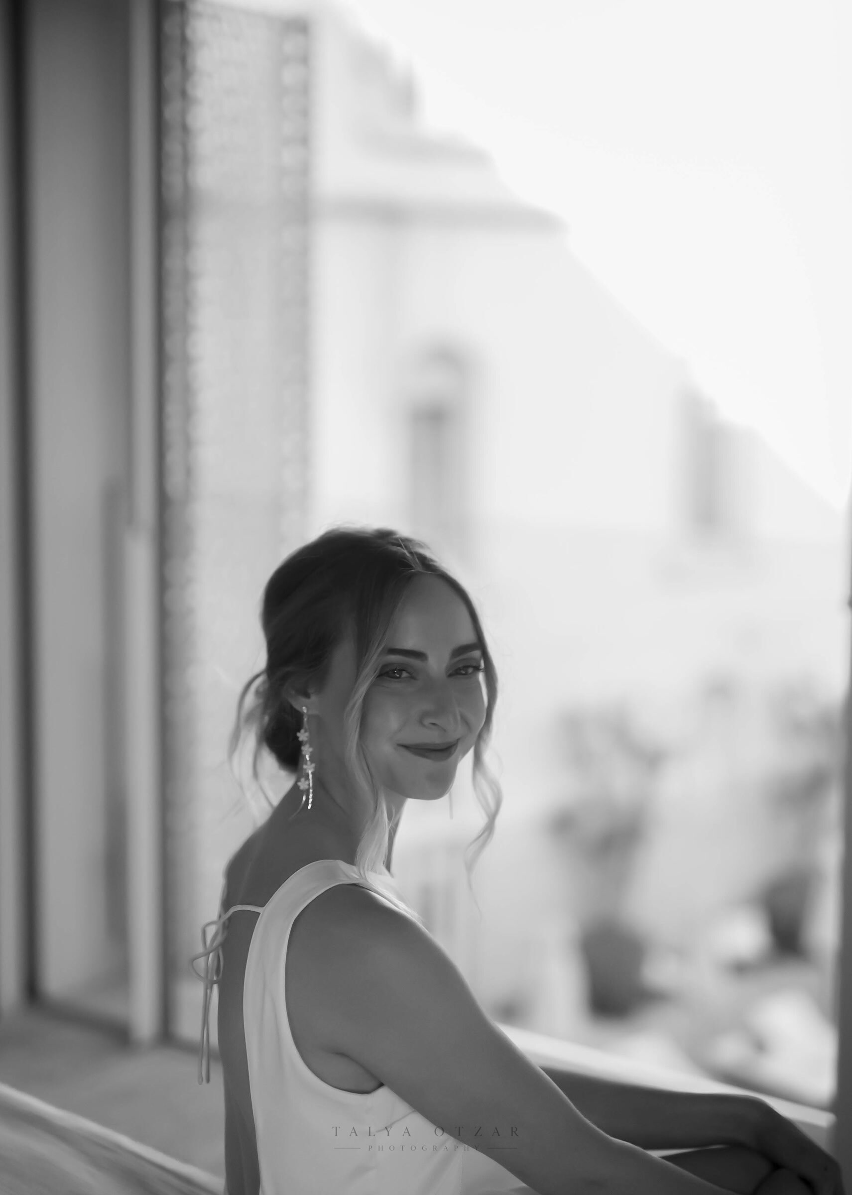 The bride glancing back over her shoulder by the window before the ceremony
