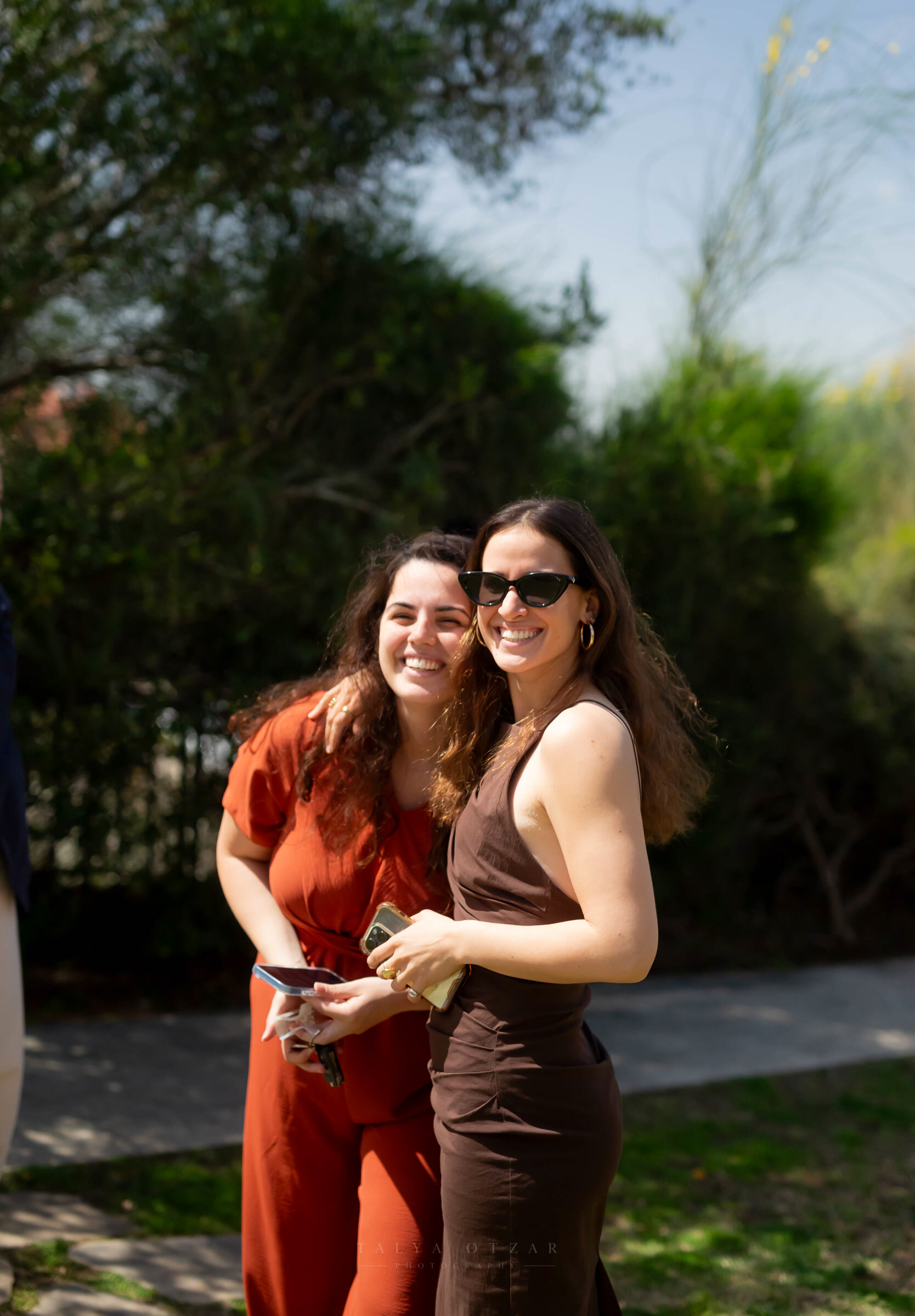 Two guests laughing arm in arm in the sunshine