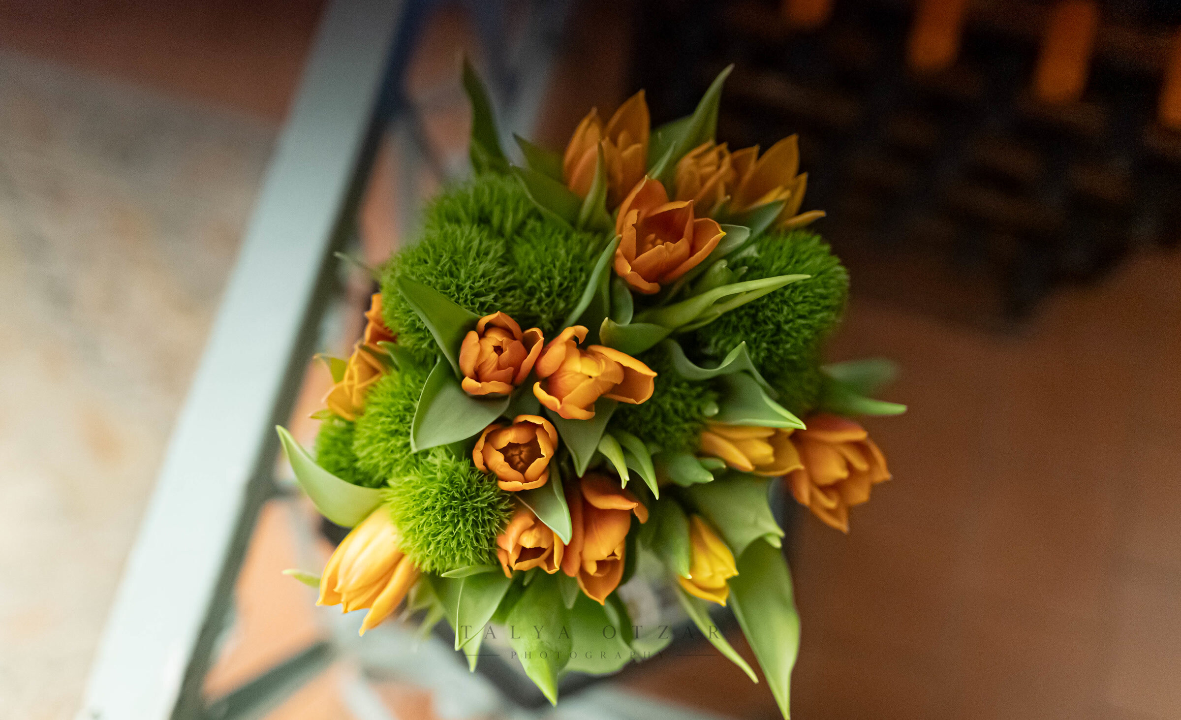 A bouquet of orange tulips and green chrysanthemums photographed from above