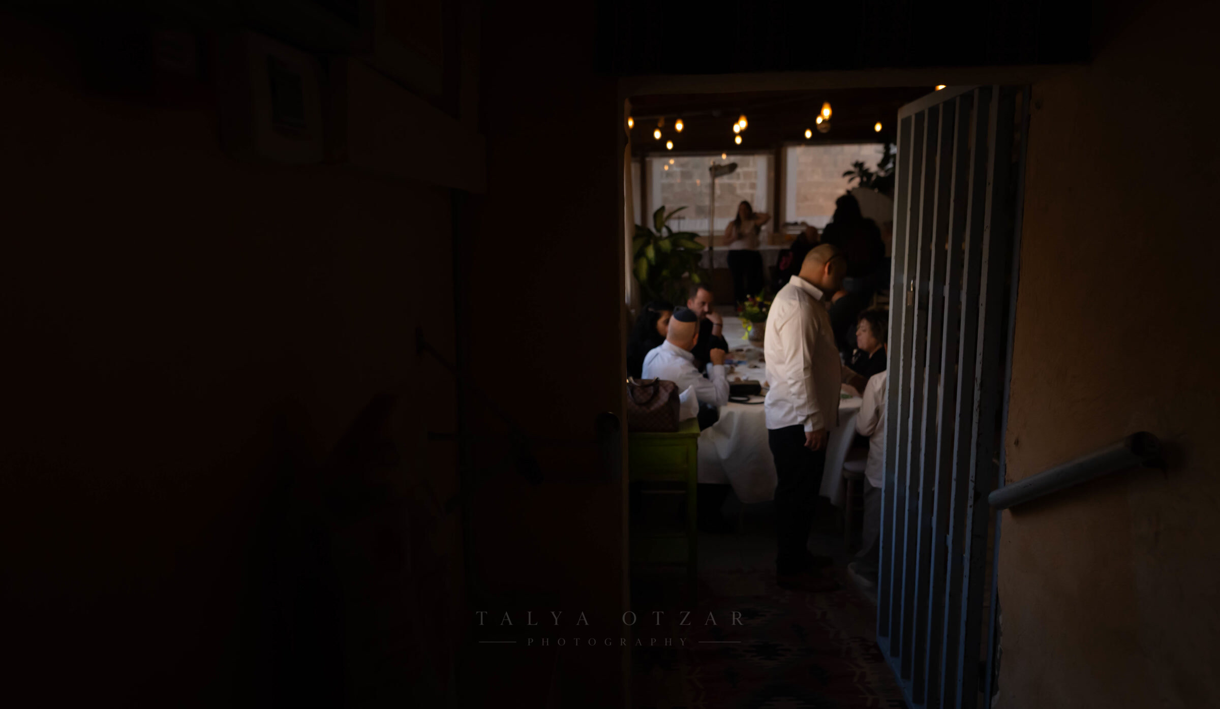 The lit dining room seen from the dark through an open doorway